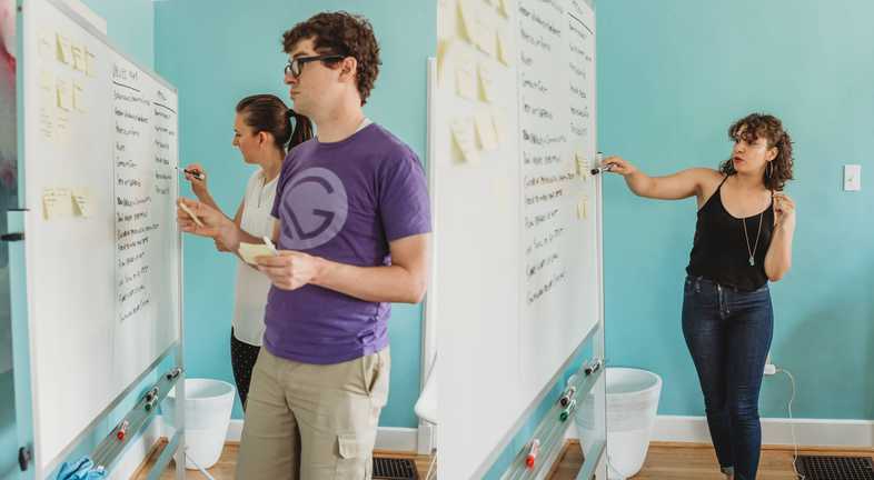 Kyle, Linda, and Marisa adding and grouping ideas on the whiteboard.